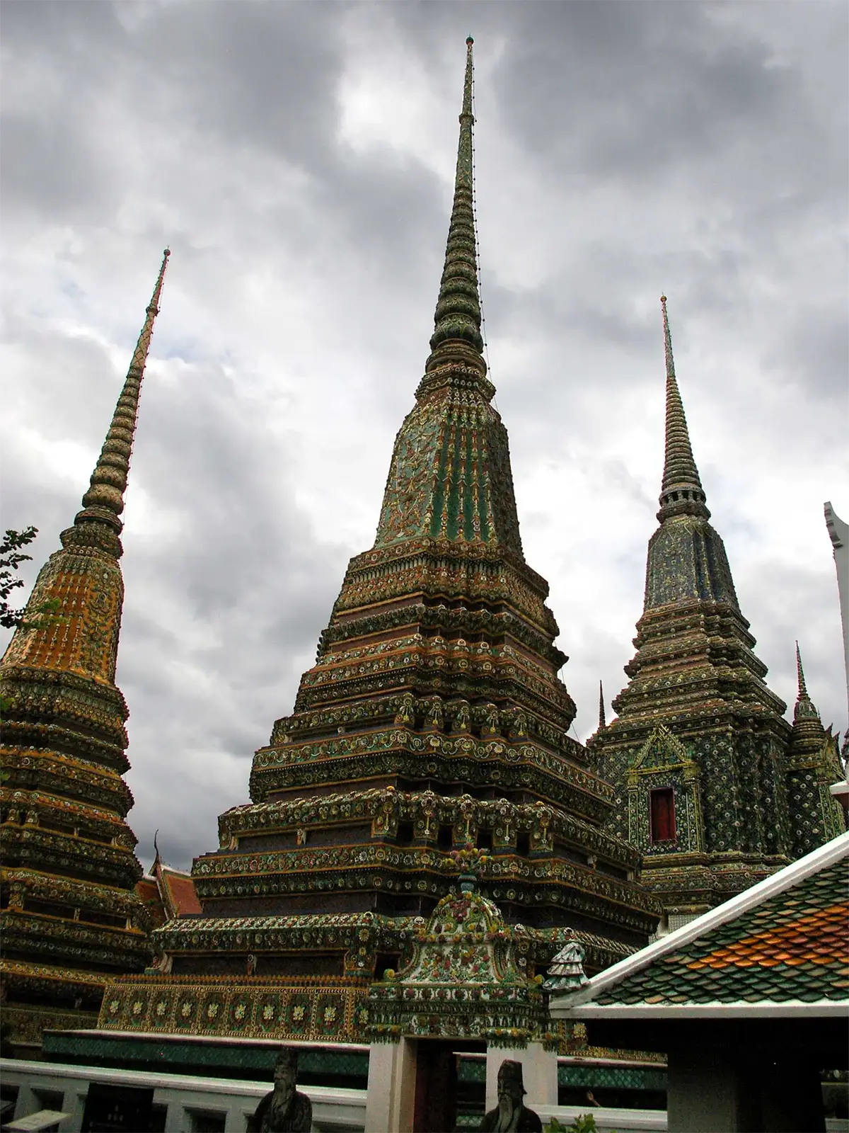 Les grands chedis couverts de céramique du Wat Pho sous un ciel d’orage à Bangkok