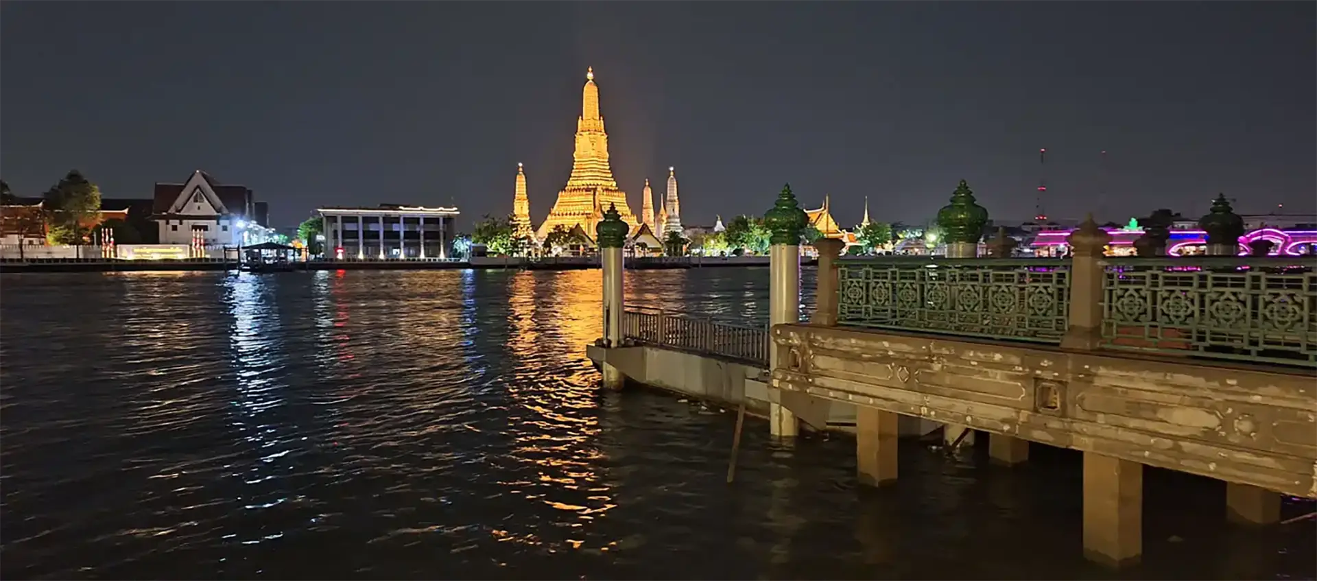 Le Wat Arun illuminé de nuit au bord de la Chao Phraya à Bangkok