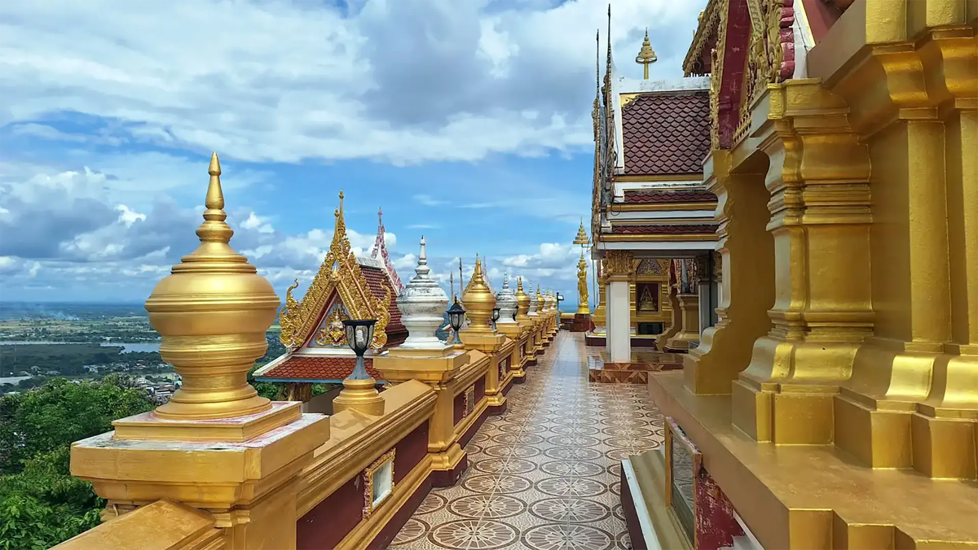 Terrasse aux ornements dorés d’un temple perché sur une colline dominant la plaine de Nakhon Sawan