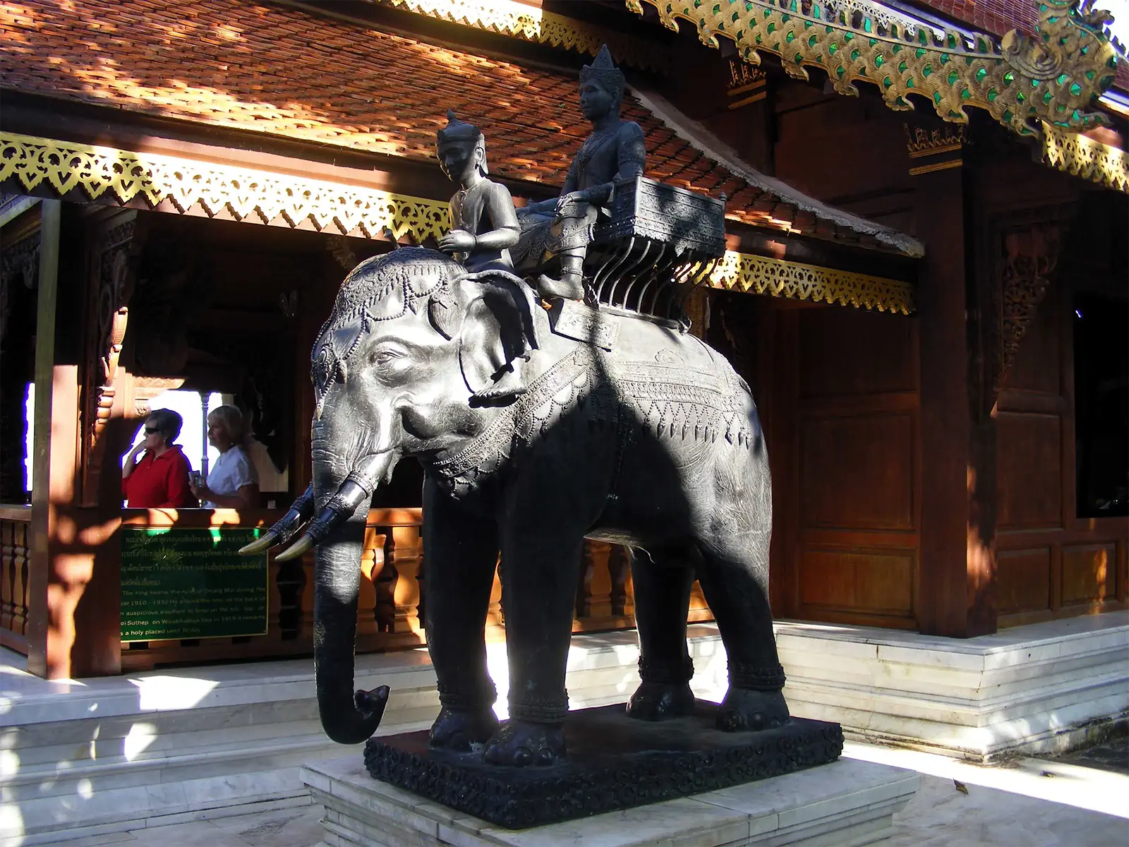 Statue d’éléphant en bronze montée par deux cavaliers devant un pavillon en bois, région de Chiang Mai
