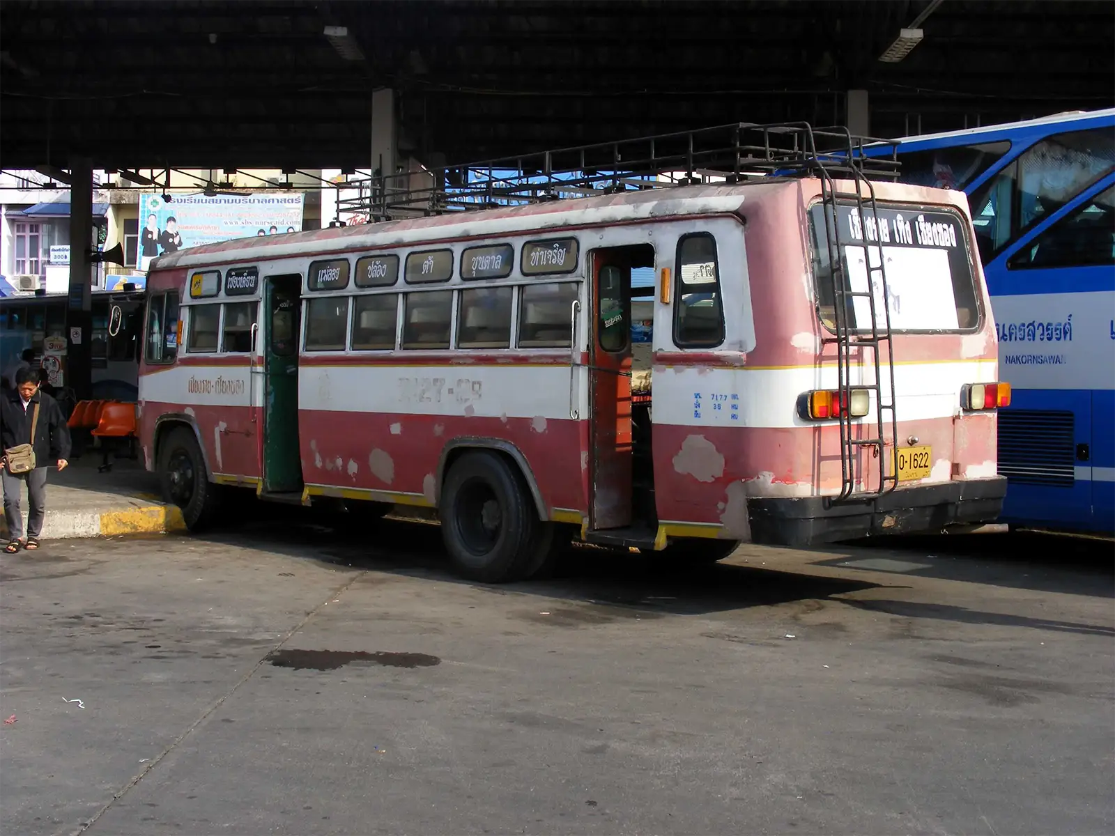 Vieux bus local rouge et blanc à quai dans une gare routière du nord de la Thaïlande