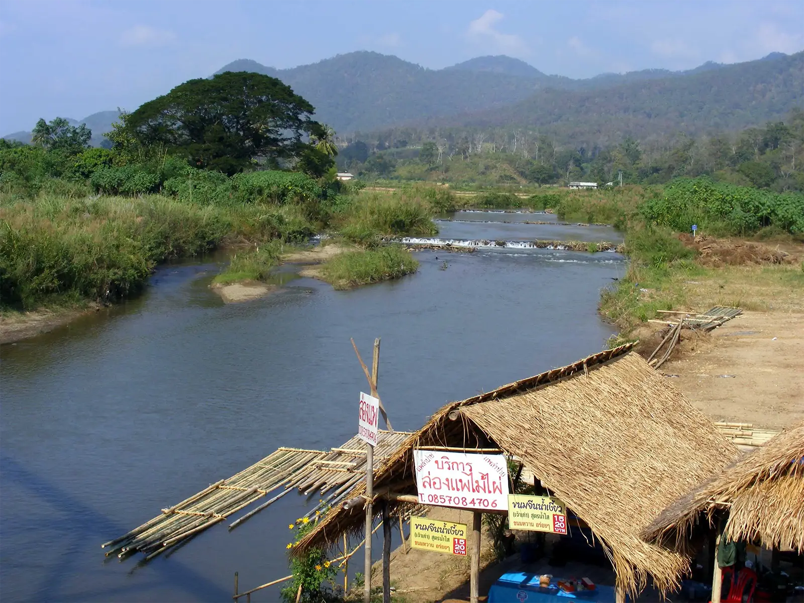 Rivière, cabanes en chaume et radeaux de bambou au pied des montagnes du nord de la Thaïlande