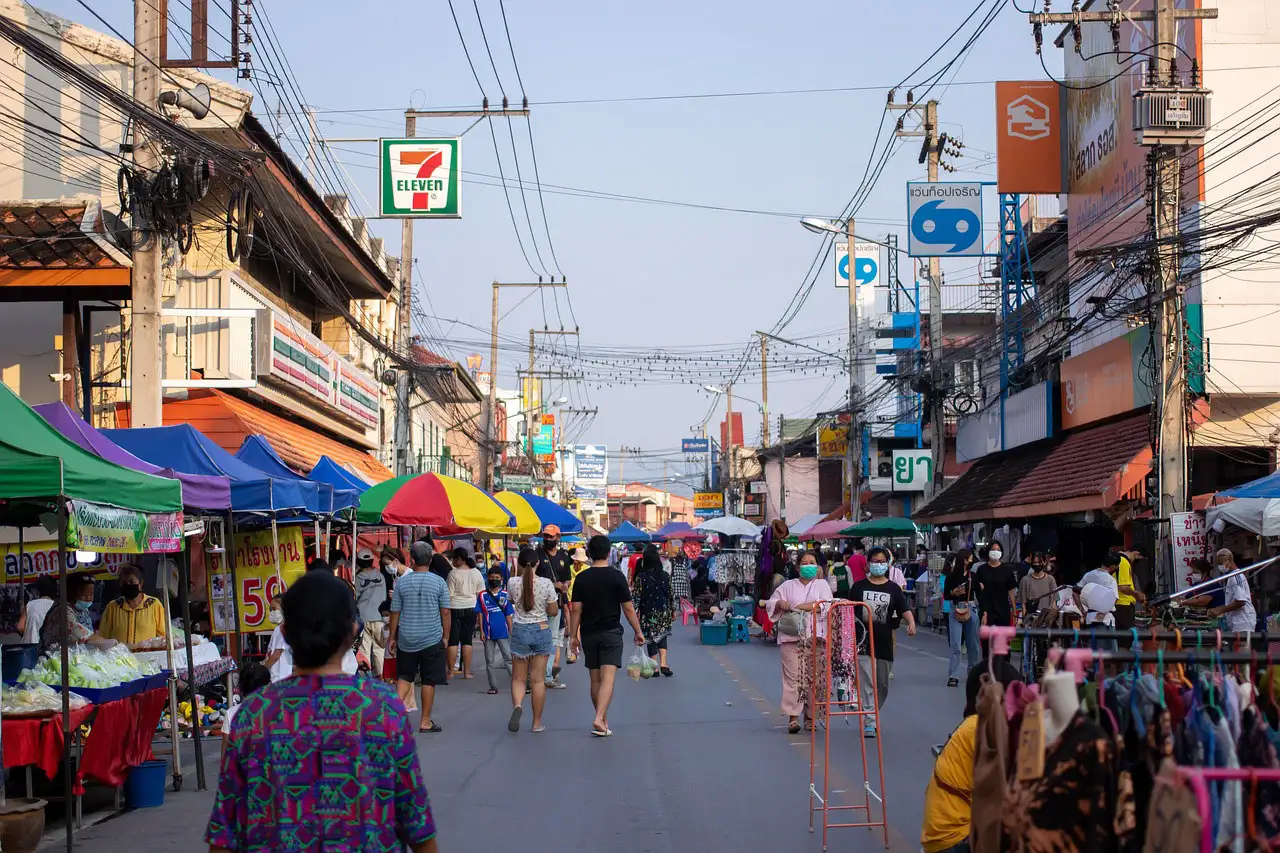 Marché de rue animé sous les fils électriques et les parasols colorés à Chiang Mai