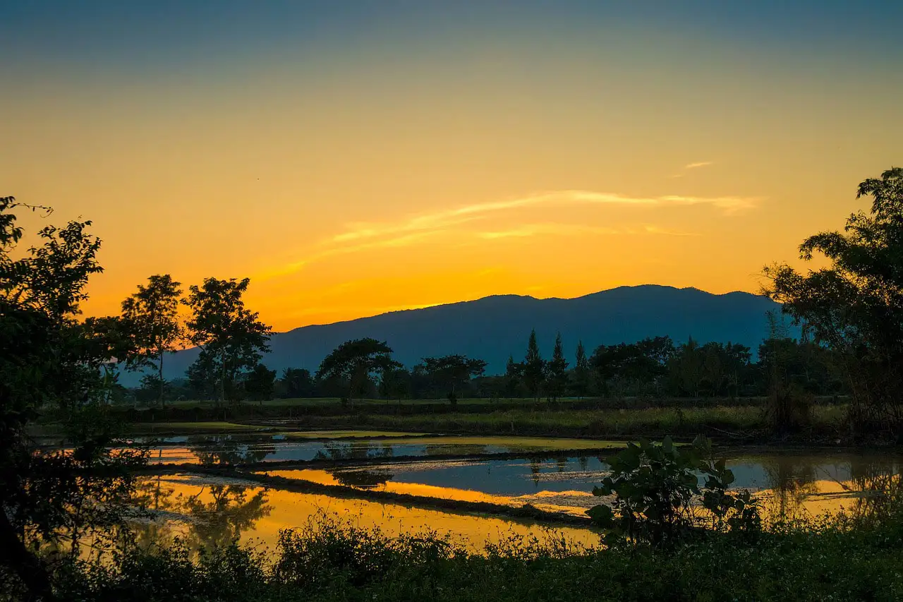 Coucher de soleil orangé sur les rizières inondées et les montagnes aux environs de Mae Hong Son