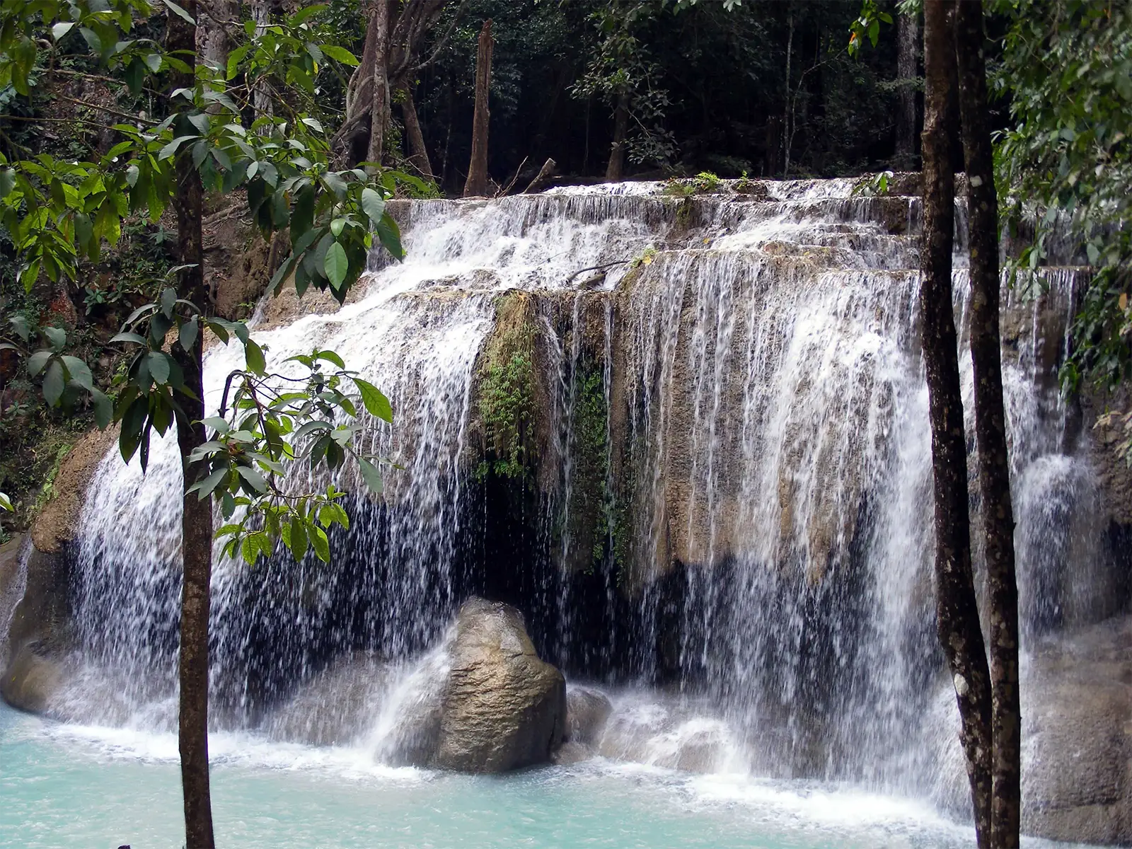 Large cascade en paliers se jetant dans un bassin turquoise en forêt près de Kanchanaburi