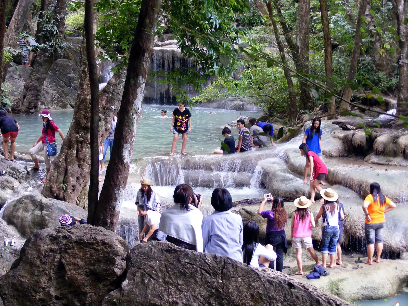 Baigneurs et promeneurs dans les vasques turquoise d’une cascade près de Kanchanaburi
