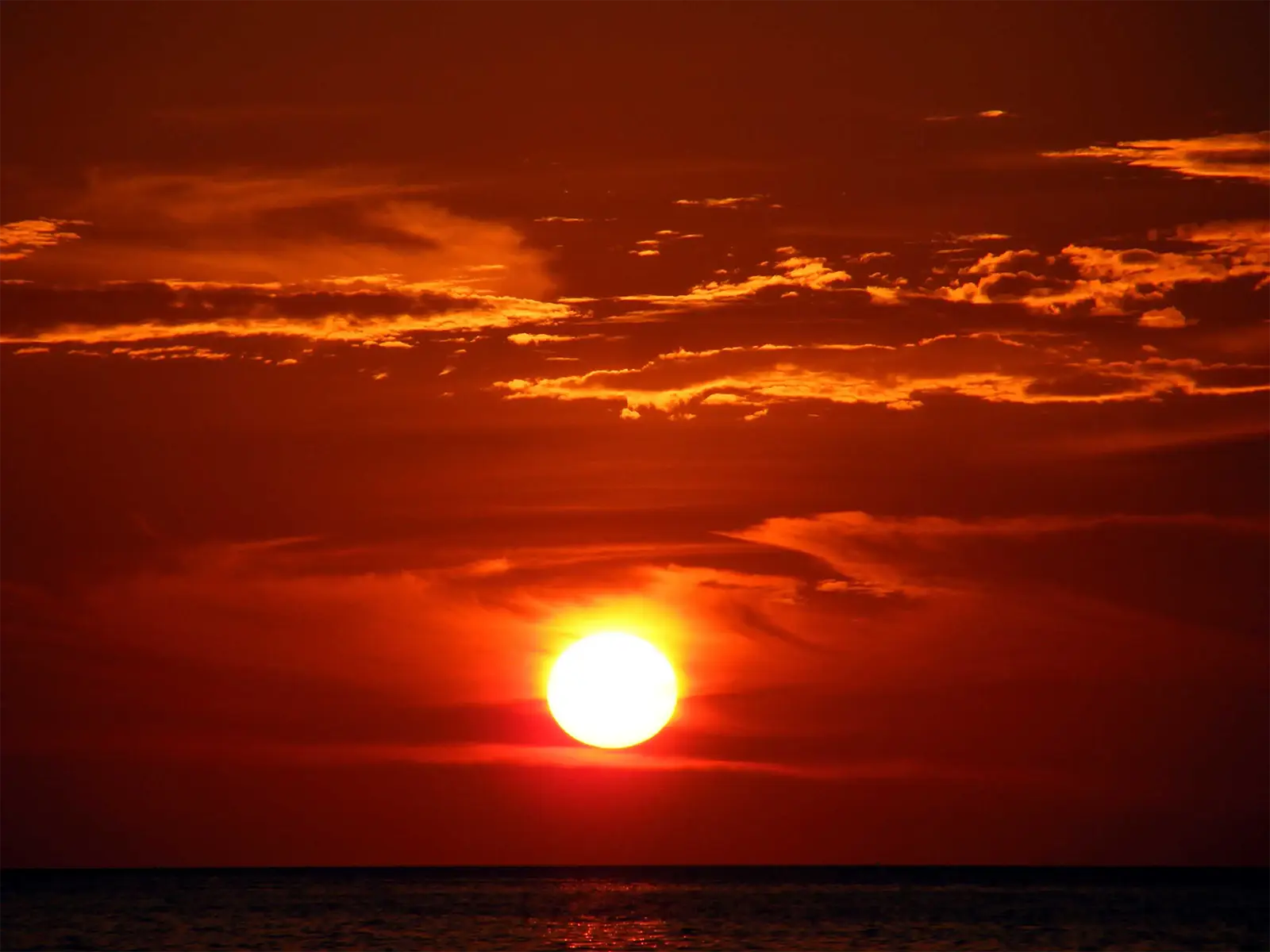 Disque du soleil rouge descendant sur l’horizon de la mer d’Andaman à Koh Lipe