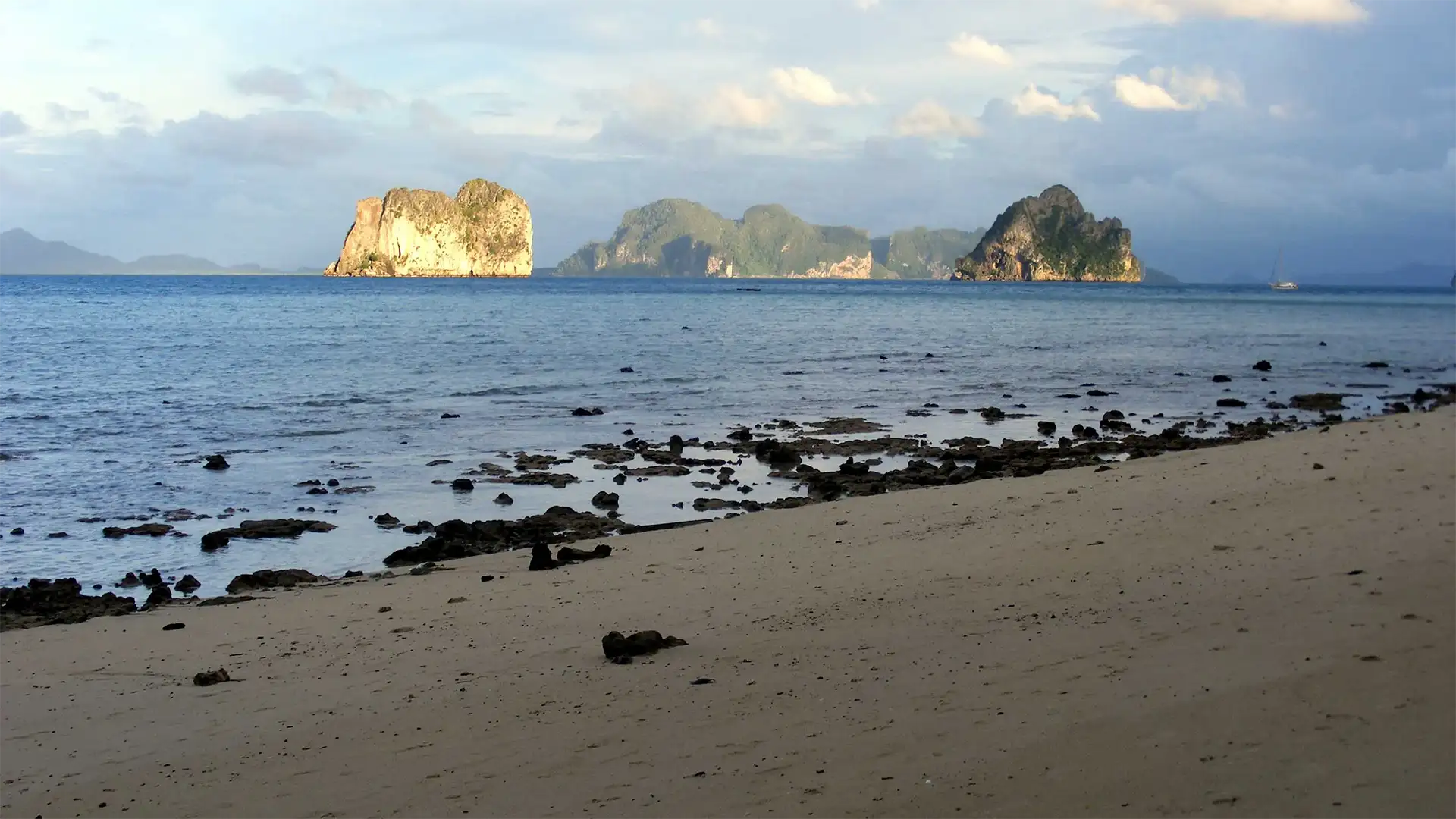 Îlots calcaires éclairés par la lumière du soir face à une plage rocheuse de Koh Ngai