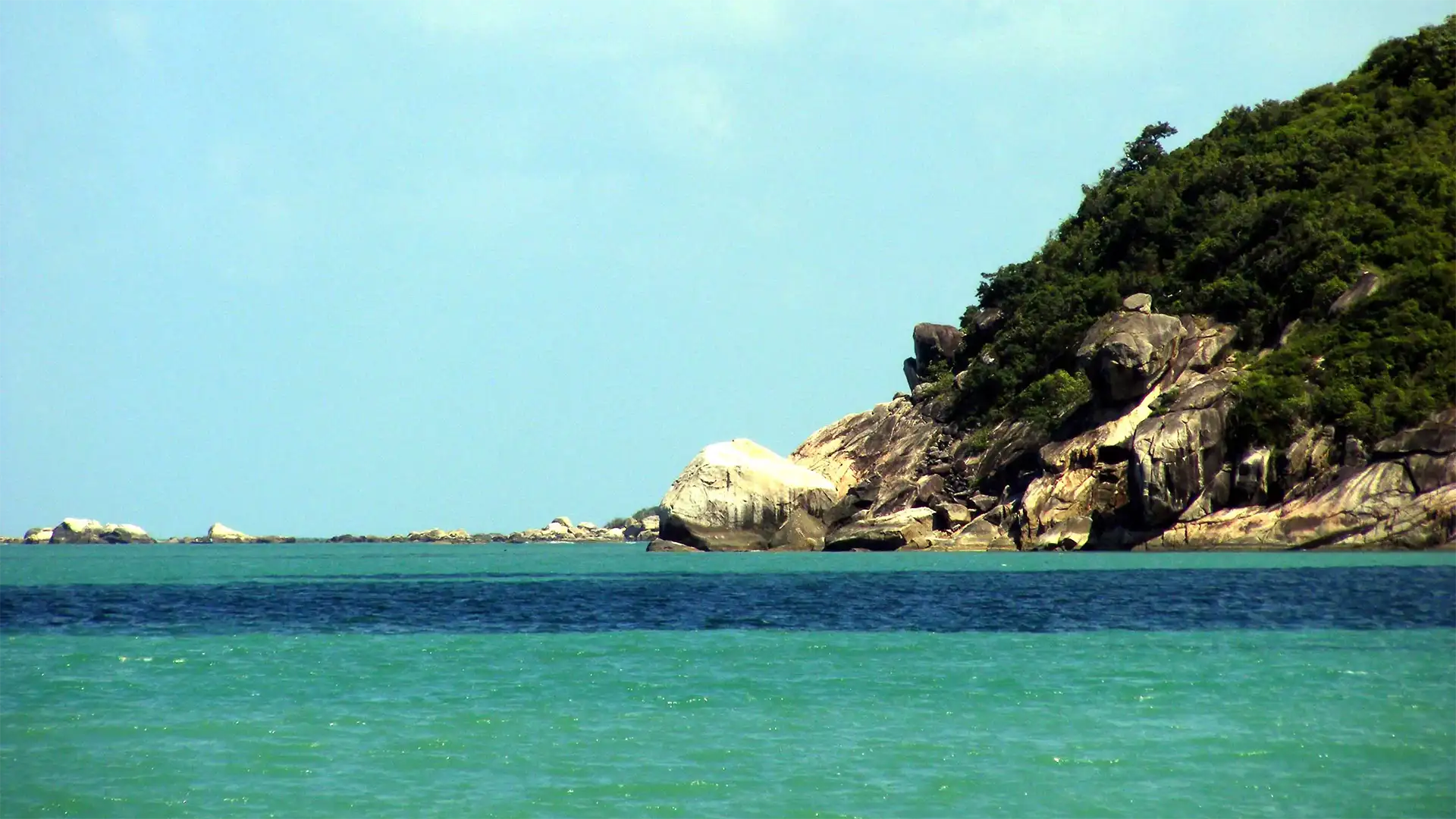 Pointe rocheuse couverte de jungle au-dessus d’une mer turquoise à Koh Phangan