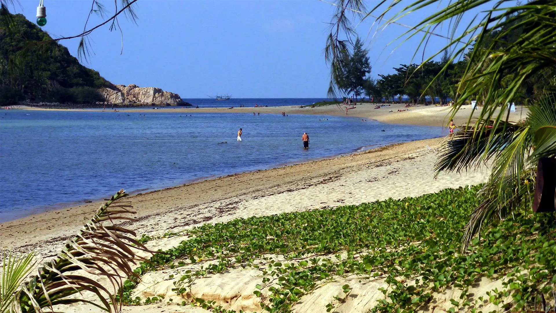 Baigneurs dans un lagon peu profond face à un promontoire rocheux à Koh Phangan