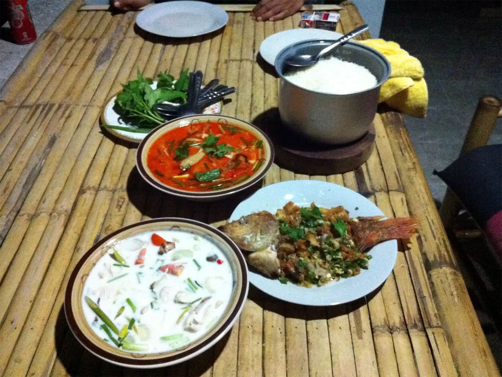 Repas thaï maison sur une table en bambou à Koh Phangan : curry, soupe, poisson frit et riz
