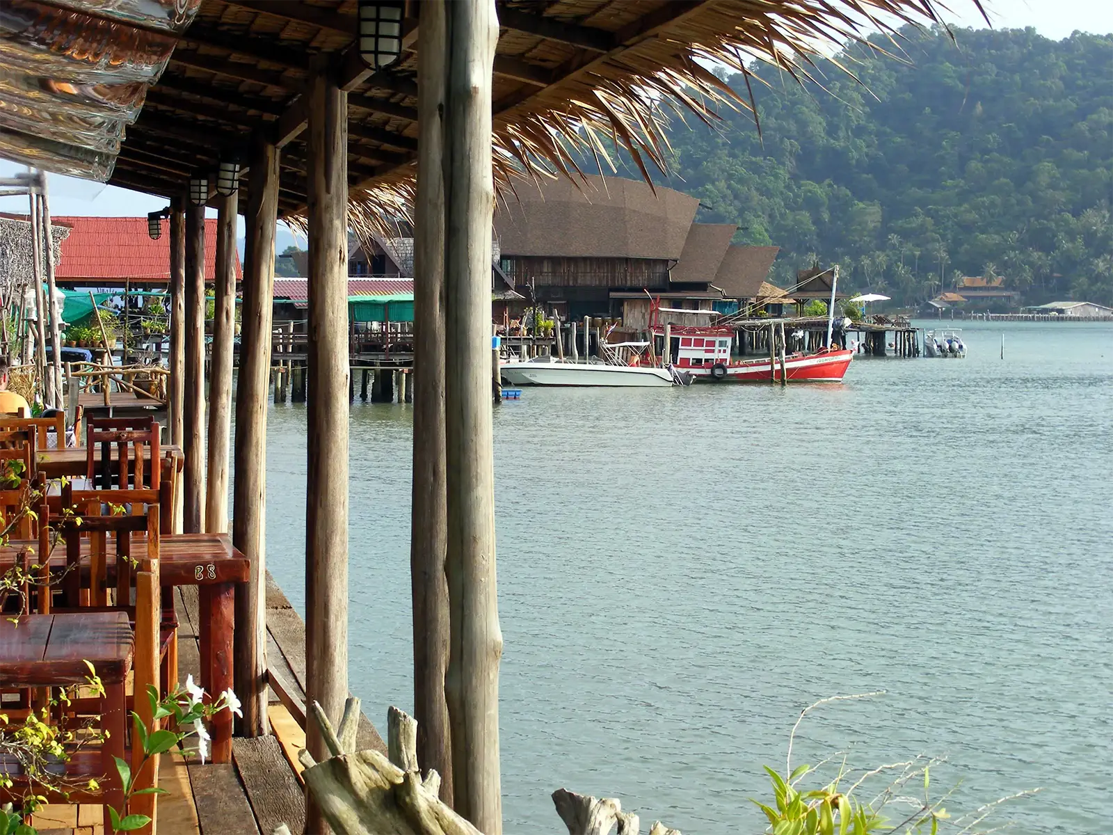 Terrasse de restaurant sur pilotis et bateaux de pêche dans un village de pêcheurs de Koh Chang