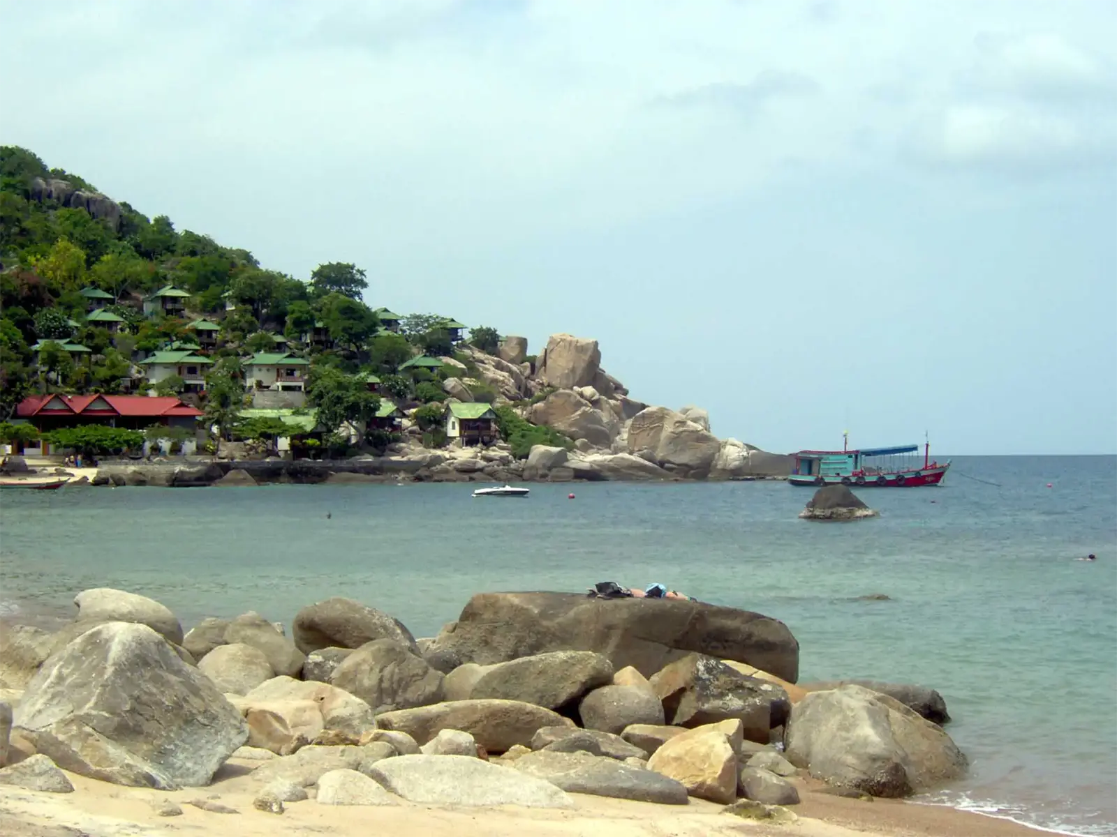 Baie bordée de gros rochers granitiques et de bungalows sur la colline à Koh Tao