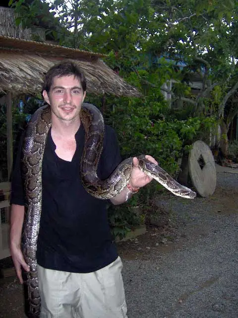 Un voyageur portant un python autour du cou dans le delta du Mékong
