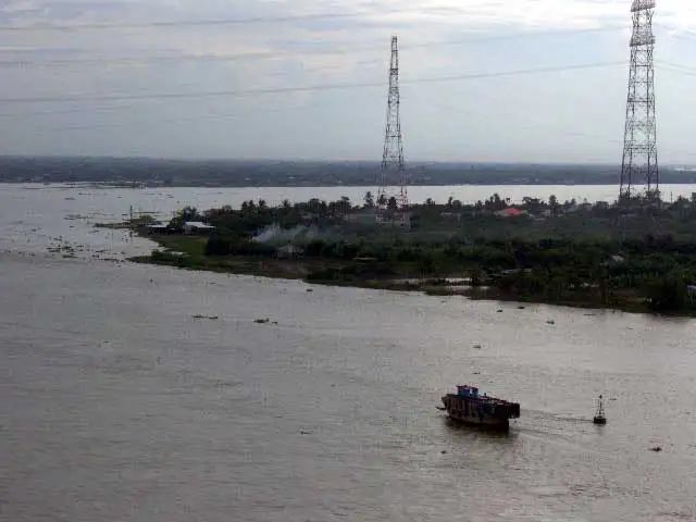 Bras du Mékong, île boisée et pylônes électriques vus d’un pont dans le delta du Mékong