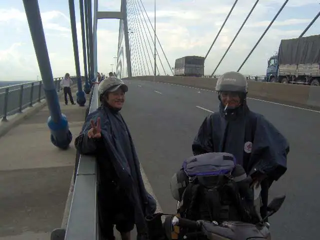 Deux motards en poncho de pluie sur un pont à haubans du delta du Mékong