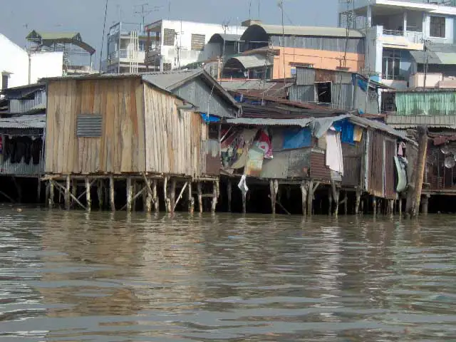 Maisons sur pilotis en bois et en tôle au bord du fleuve, dans le delta du Mékong