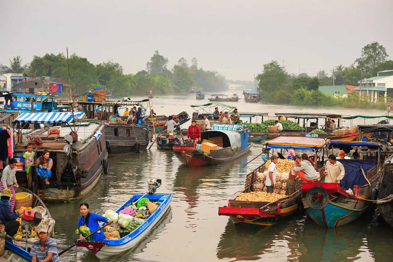 Marché flottant au petit matin, barques chargées de fruits et légumes, dans le delta du Mékong