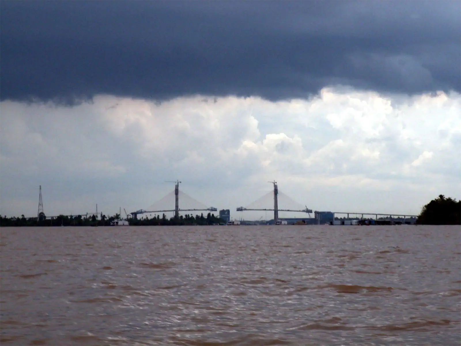 Ciel de mousson noir au-dessus d’un pont à haubans en construction sur le Mékong