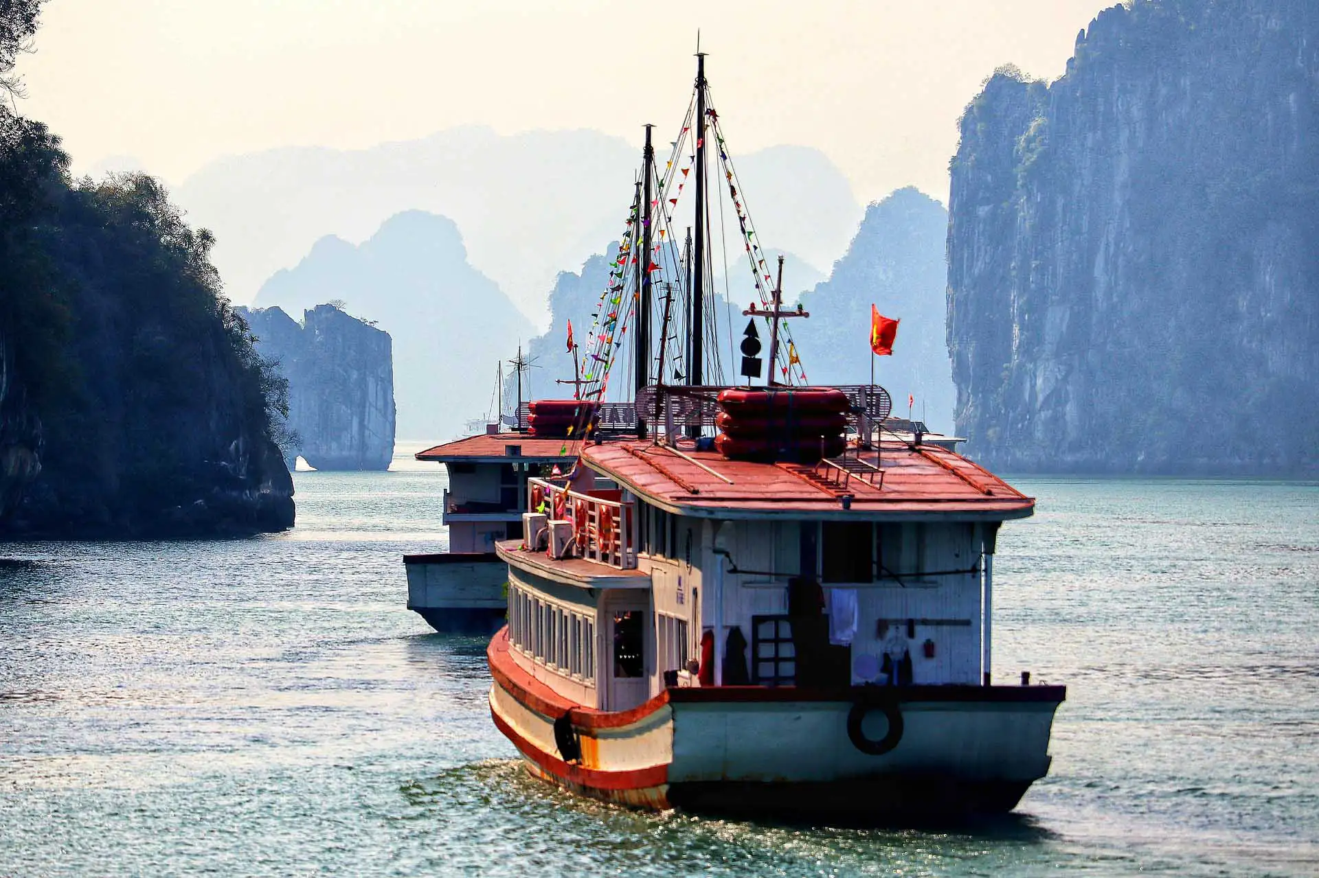 Bateaux de croisière pavoisés entre les îlots karstiques de la baie d’Halong