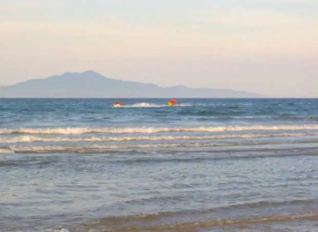 Jet-skis sur la mer de Chine et île montagneuse au loin, depuis la plage de Hoi An