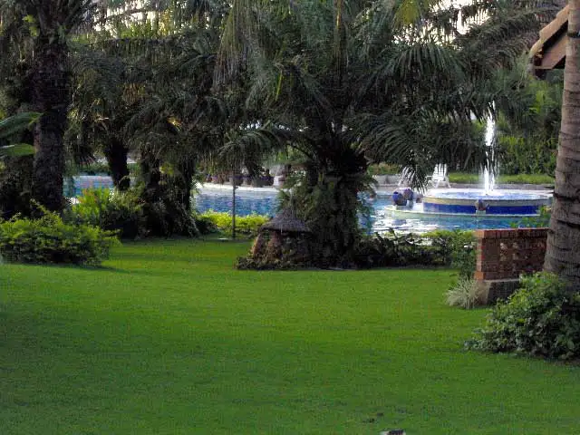 Pelouse, palmiers et fontaine dans les jardins d’un hôtel de Hoi An