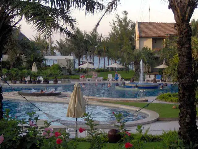Piscine et transats sous les palmiers d’un hôtel en bord de mer à Hoi An
