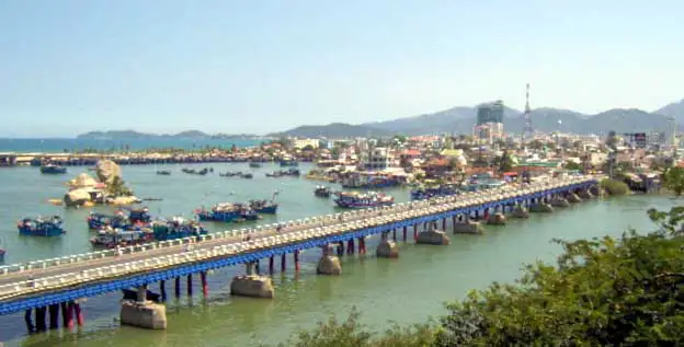 Pont et bateaux de pêche bleus sur la rivière à l’entrée de Nha Trang