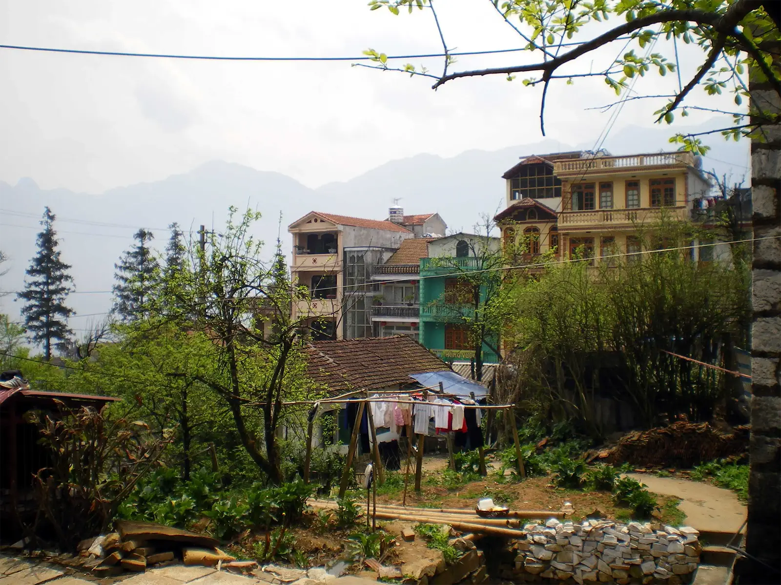 Maisons colorées et linge qui sèche devant les montagnes, dans la brume de Sa Pa