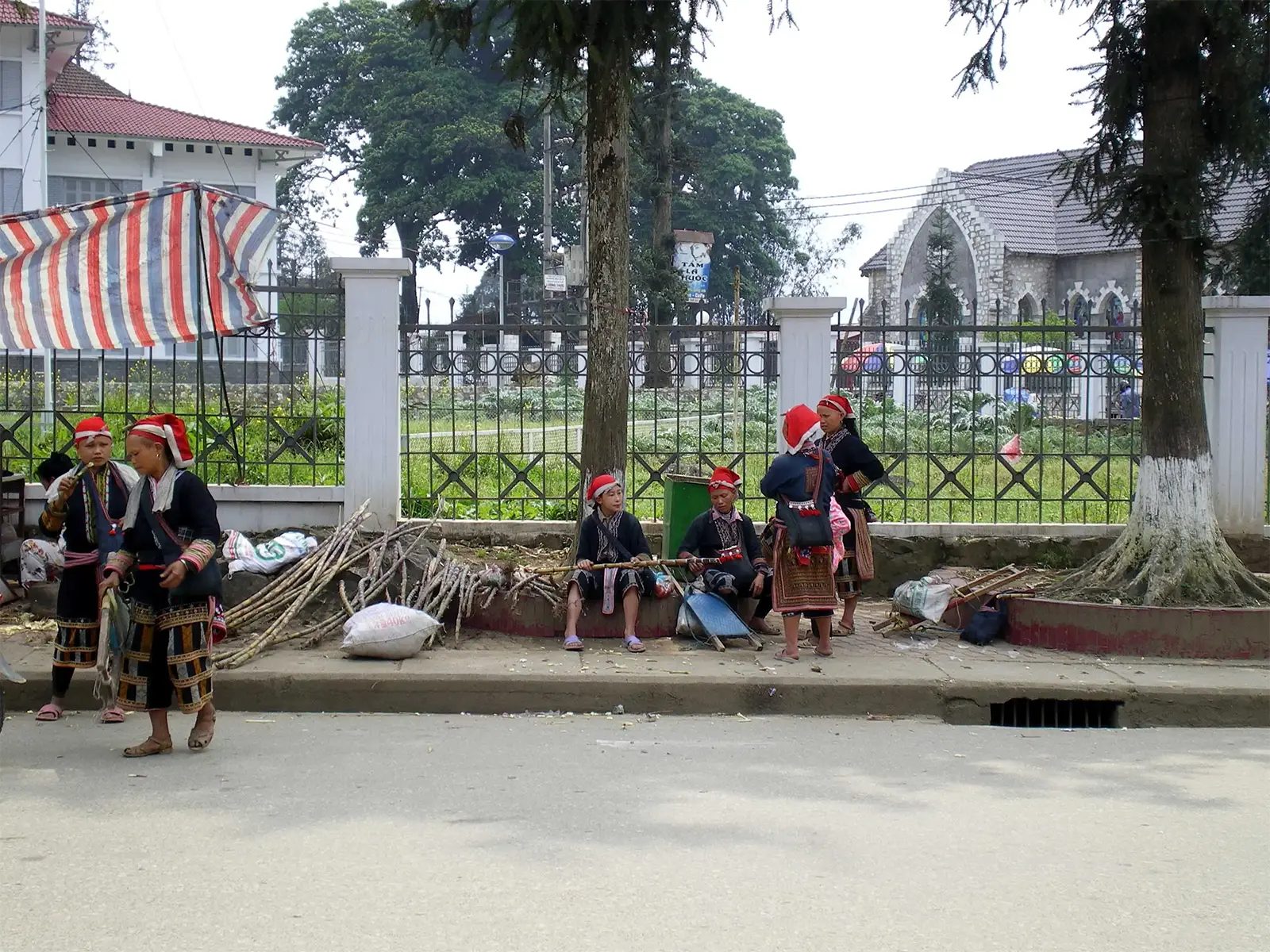 Femmes dao à la coiffe rouge en habit traditionnel au bord d’une rue de Sa Pa