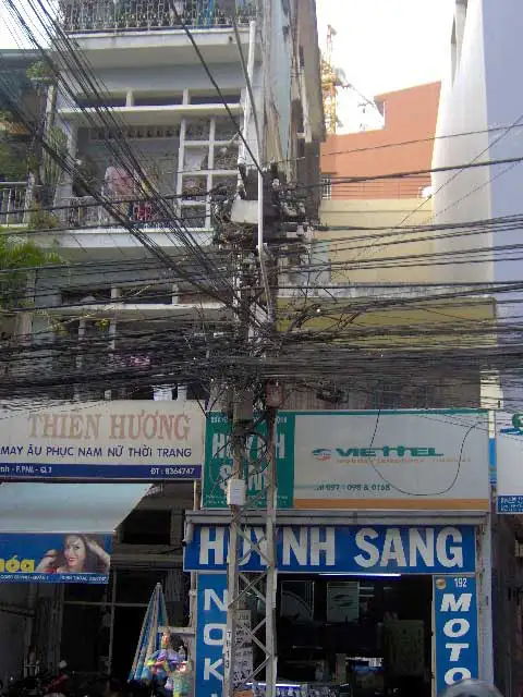Enchevêtrement de câbles électriques devant des boutiques de Saïgon