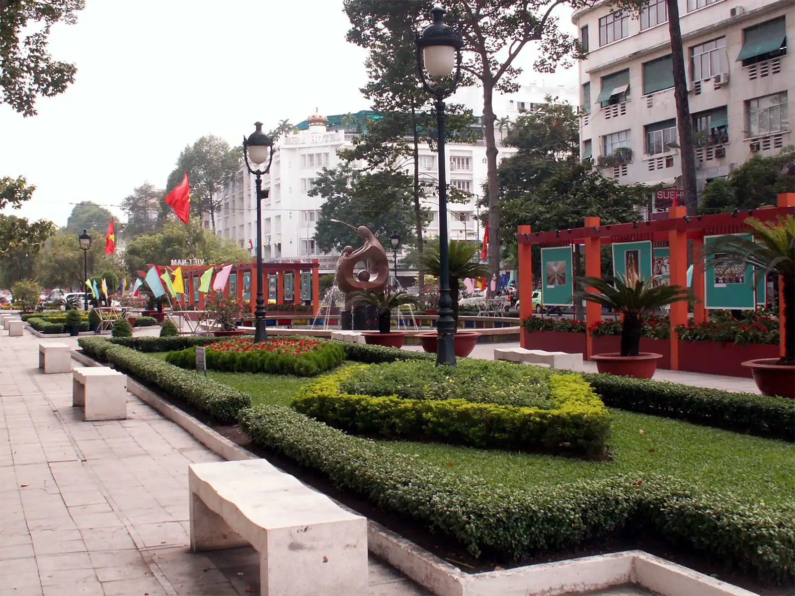 Jardin public fleuri avec sculpture et pavillons rouges dans le centre de Saïgon