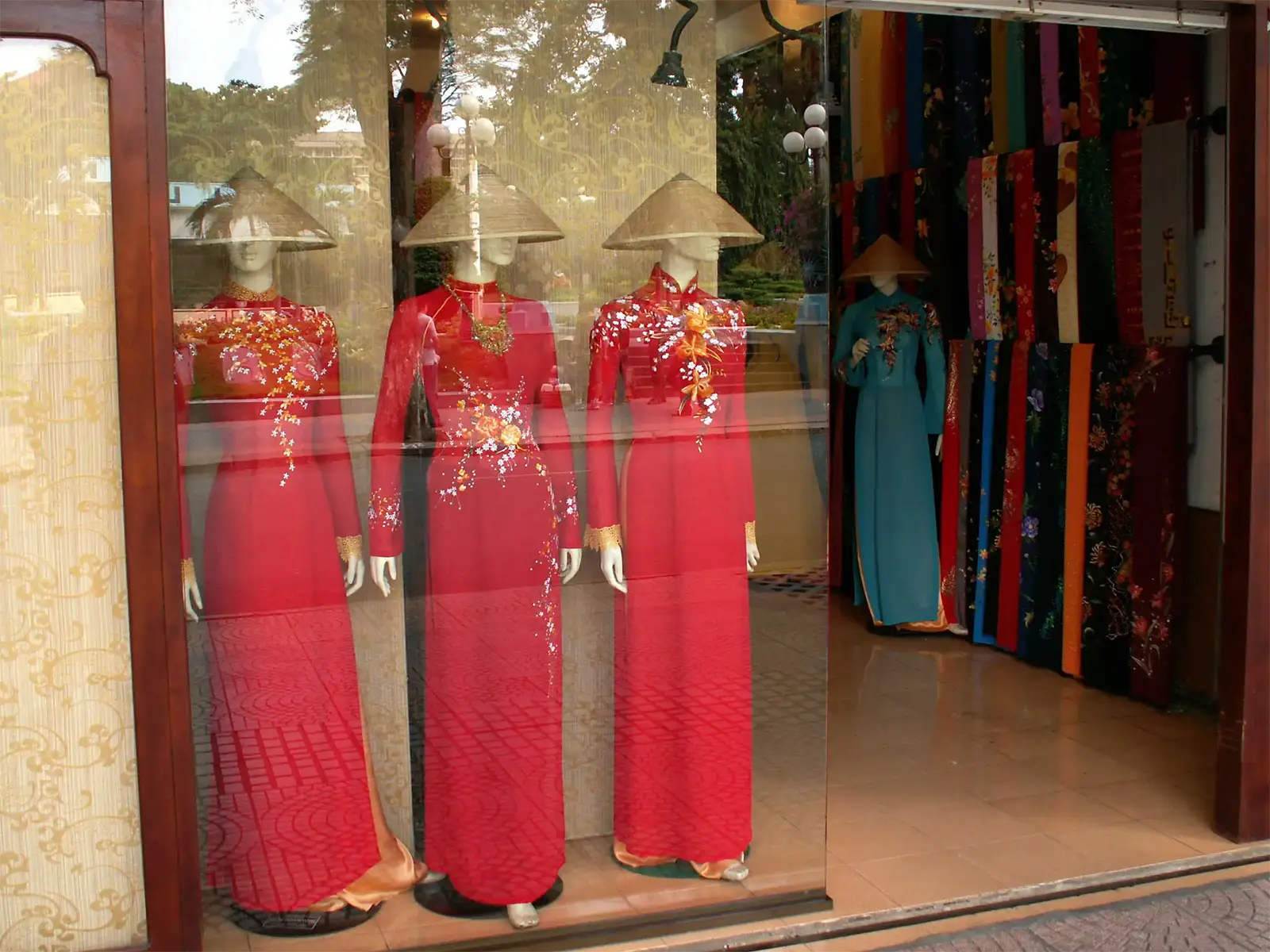 Áo dài rouges brodés et chapeaux coniques dans la vitrine d’une boutique de Saïgon