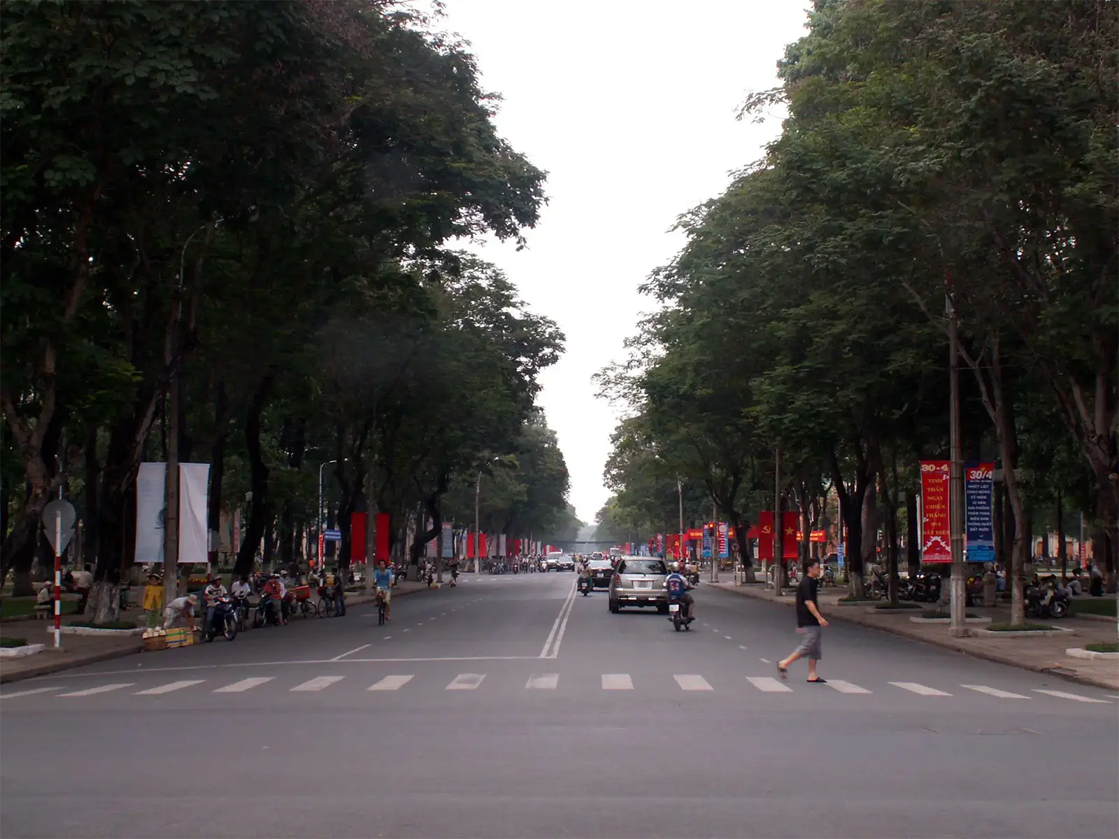 Grand boulevard ombragé par de hauts arbres dans le centre de Saïgon