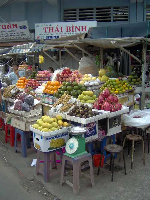 Étal de fruits tropicaux, fruits du dragon, mangues et oranges sur un marché de Saïgon